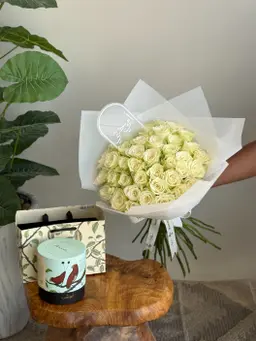 A bouquet of white roses with chocolate and a plant